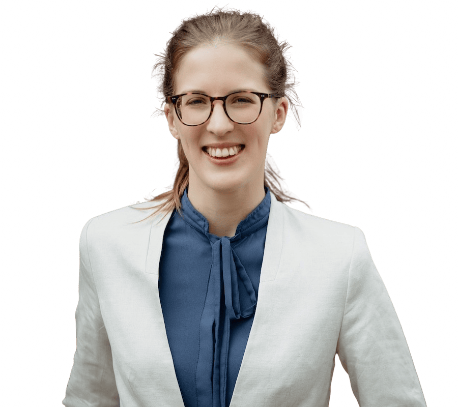 Porträt von Katharina Haas, die eine Brille, eine blaue Bluse und einen weißen Blazer trägt